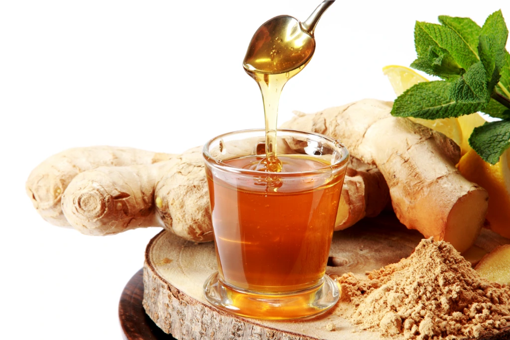 ginger tea with a spoonful of honey and fresh ginger on a wooden board