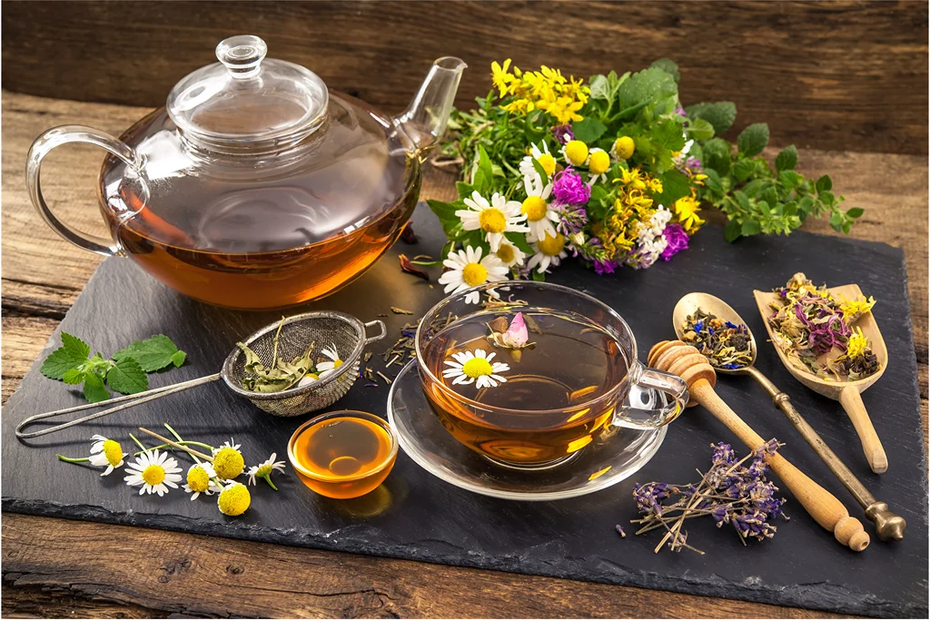 a pot and a cup of tea on a stone slab with fresh flowers