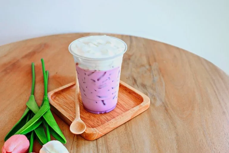 Taro Boba Milk Tea is placed on a wooded coaster with a flavor on the side