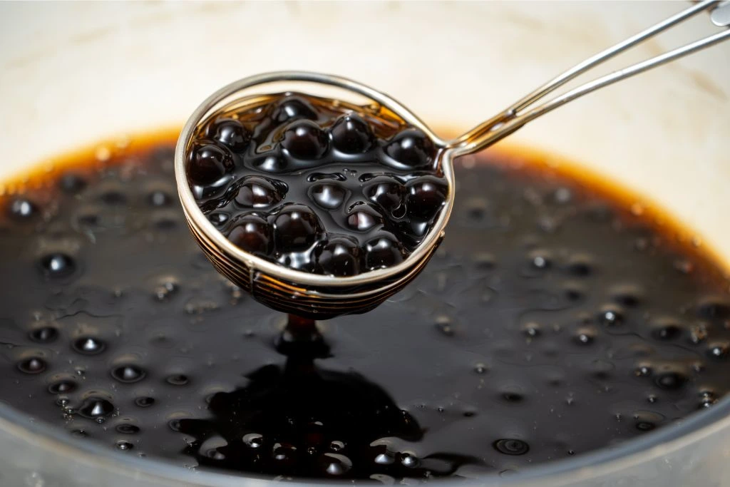 a scoop of tapioca pearls over a bowl on tapioca pearls in syrup