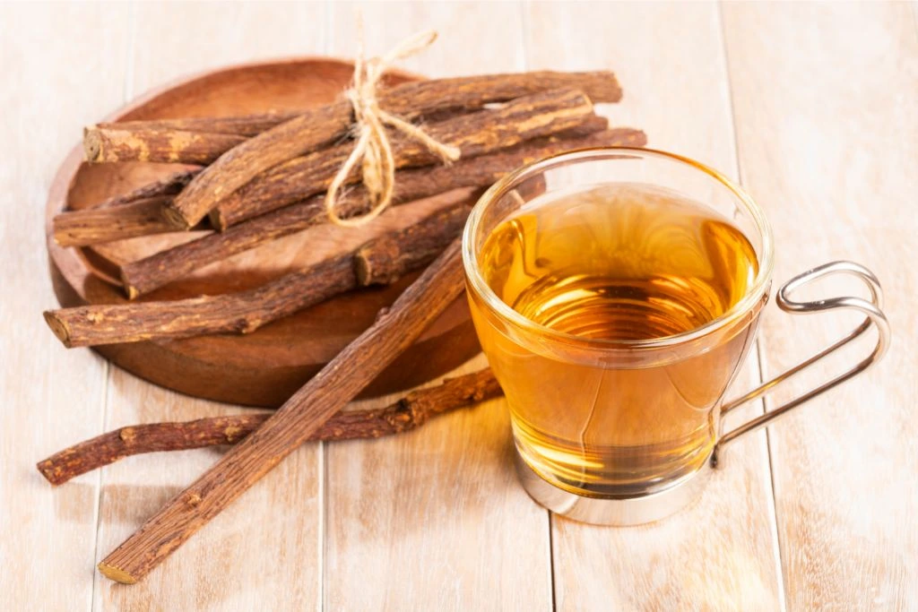 a cup of licorice tea with licorice roots on a wooden table