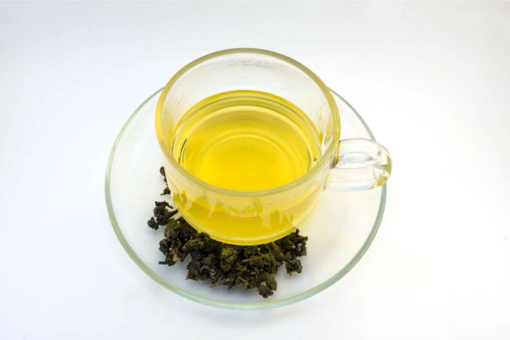 a cup of oolong tea with dried oolong on the side
