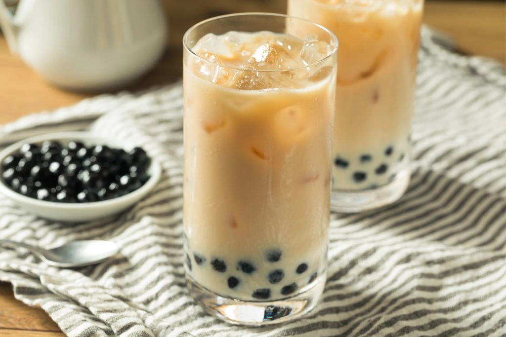 Refreshing Homemade Oolong Milk Tea placed in 2 glass cups with a bowl of tapioca pearls beside it