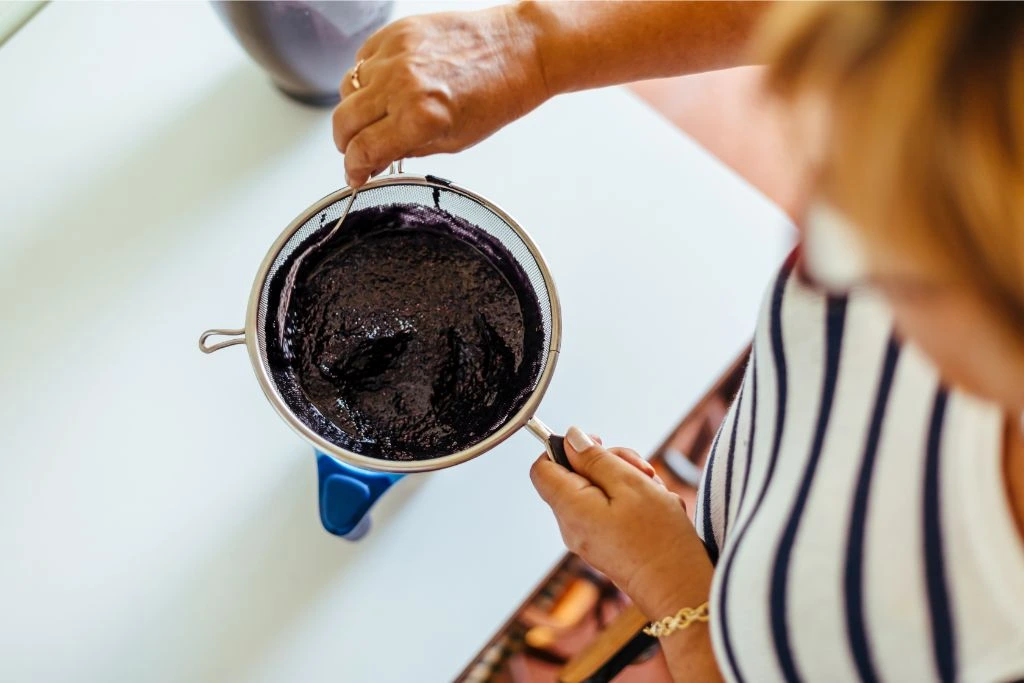 woman straining cooked black berries