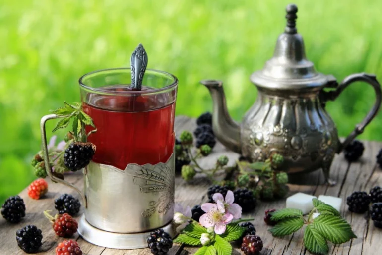 blackberry with blackberry fruits together with classic teapot placed on top of a wooden table