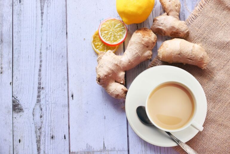 ginger milk tea together with sliced ginger placed on top of a wooden platform