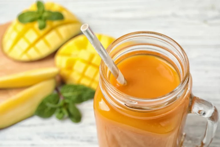 mango milk tea in front of freshly sliced mangoes