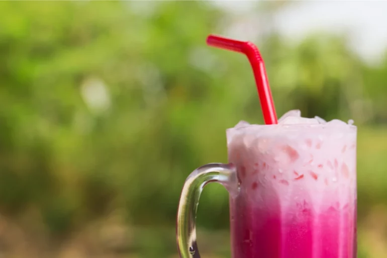 a glass of rose milk tea with a straw