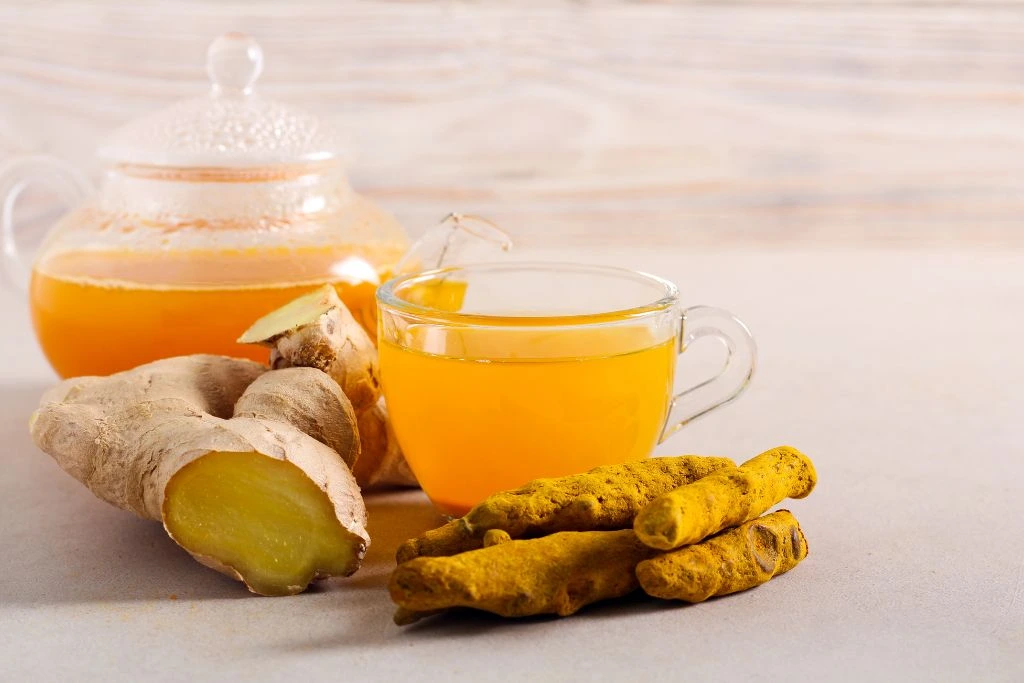 a glass of turmeric tea with some turmeric on the side