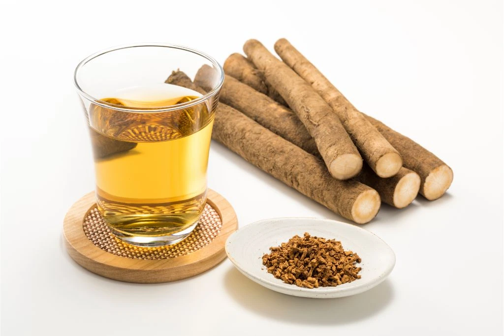 A cup of tea on a coaster with burdock roots 