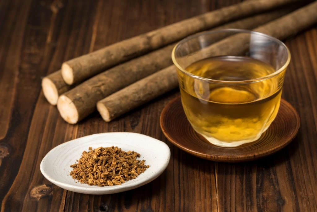 A cup of tea with burdock roots on a wooden table