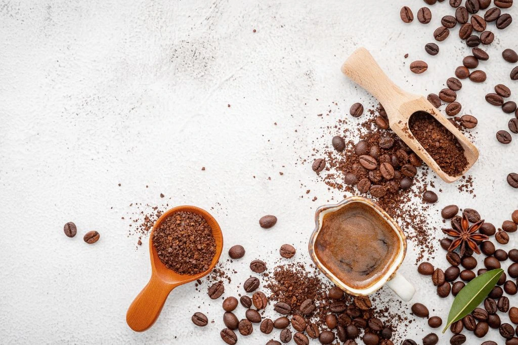 Various roasted coffee beans and grinded coffee beans in a scooper