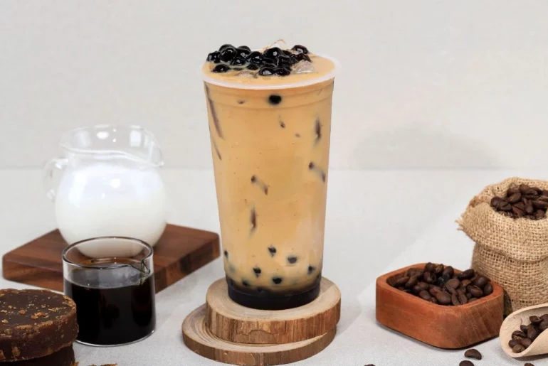 A coffee Milk tea in a cup with extra coffee and milk at the sides