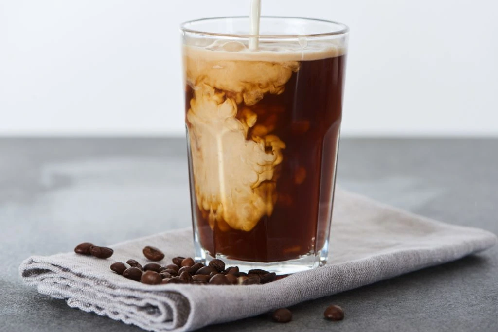 Milk pouring over a glass of coffee