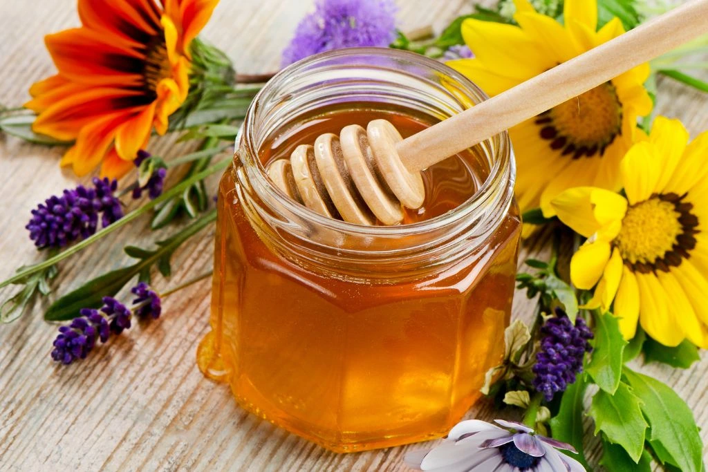 Jar of honey surrounded by sunflowers