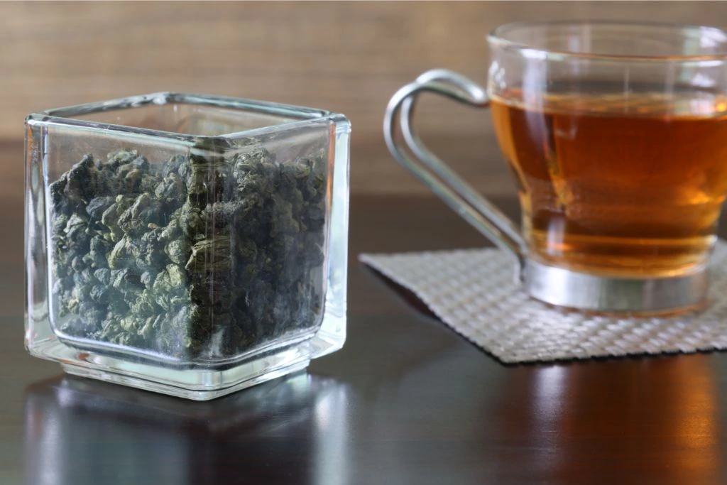 a cup of Oolang tea and tea lead on a wooden table