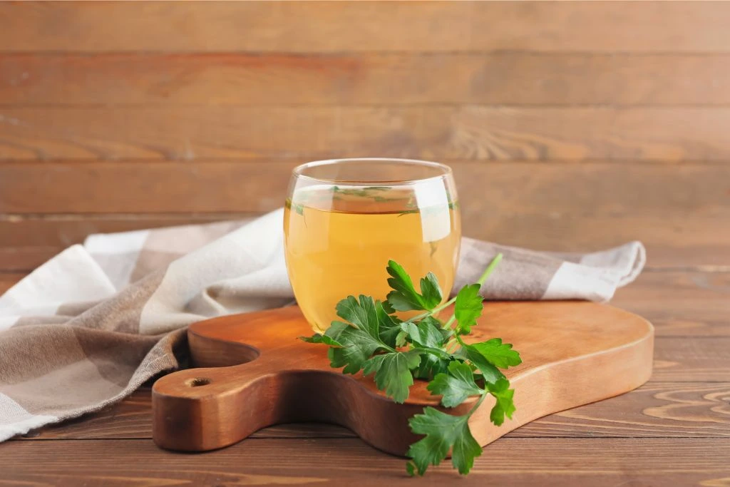 cup of hot tea and parsley on wooden background