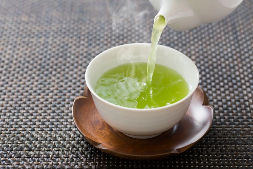 a small glass cup full of hot green tea