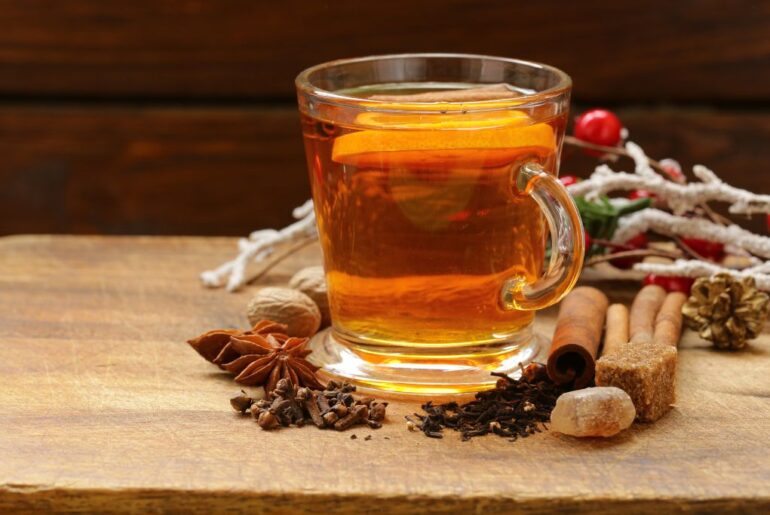 a cup of clove tea with clove spices in the side
