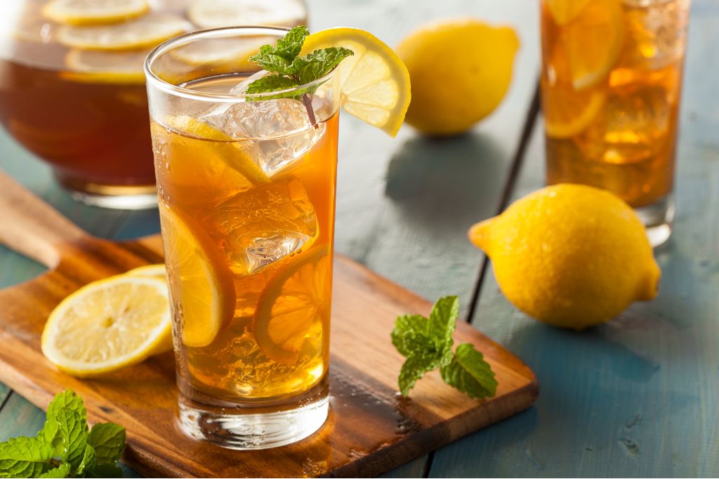 a glass of lemon iced tea with mint and slice of lemon
