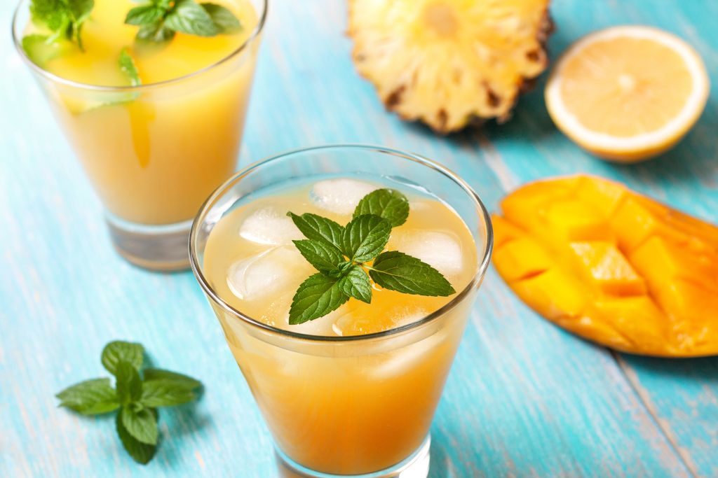 mango iced tea with mint in a glass on a blue wooden table