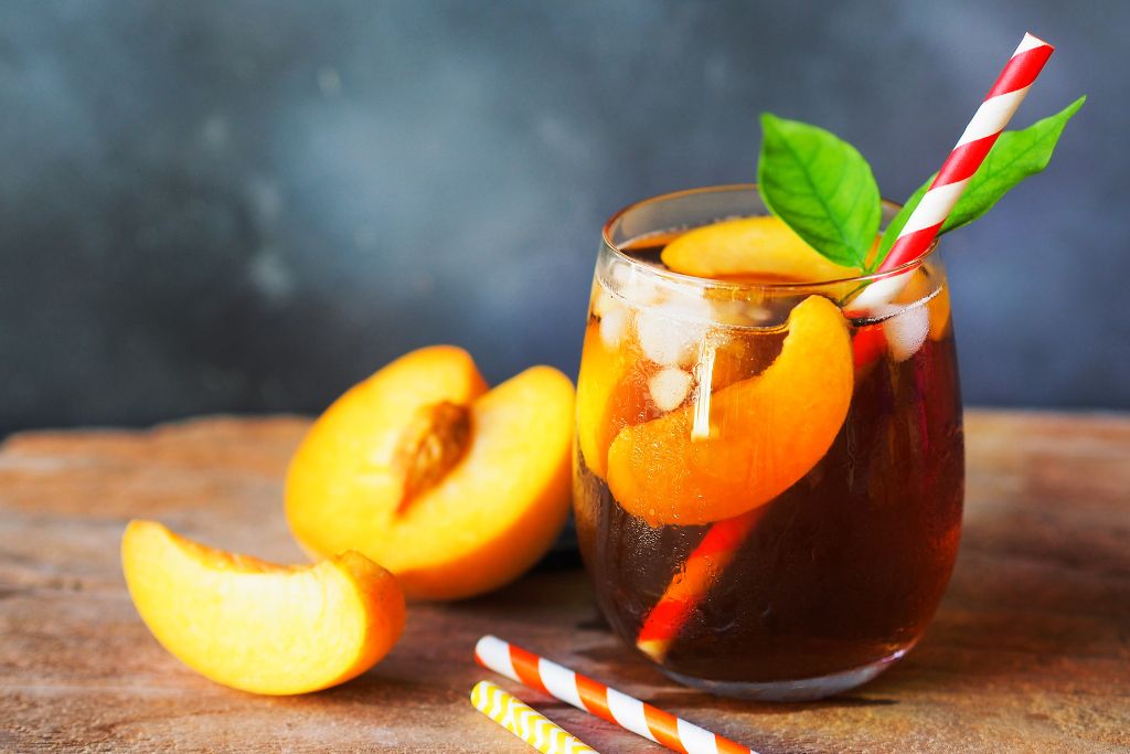 a glass of peach iced tea on a wooden table