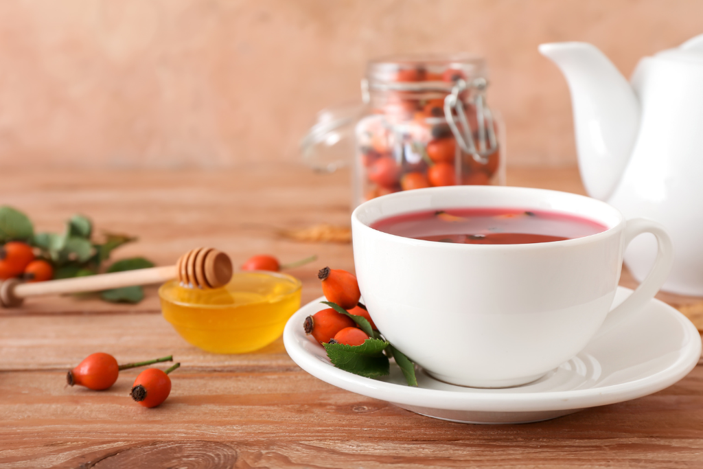 Rose Hip Tea in a wooden table with honey and rosehip fruit at the back