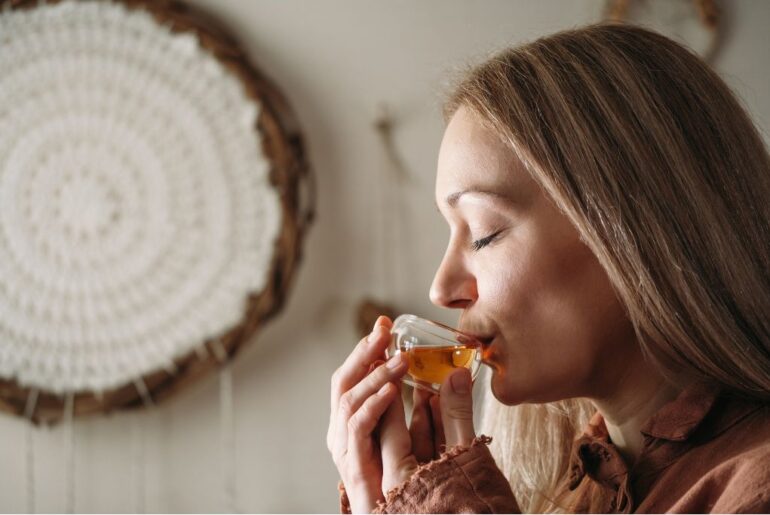 a woman drinking a hot cup of tea