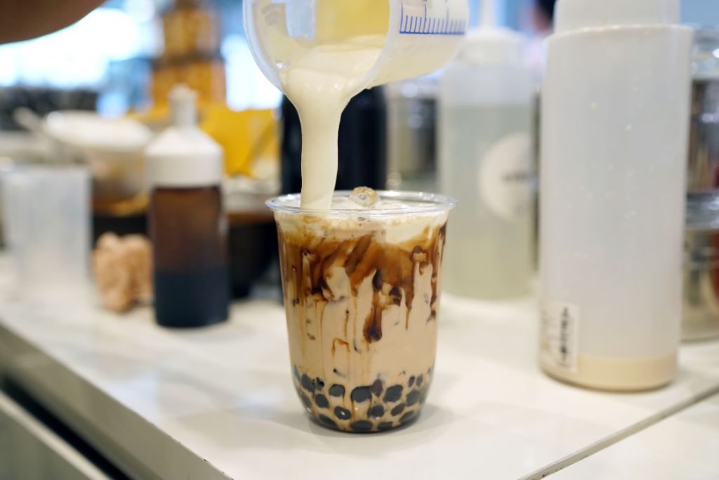 cream poured on black milk tea