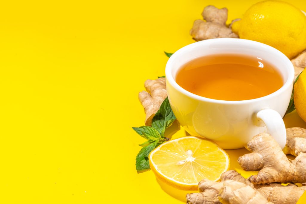 Ginger Mint Tea in a cup with lemon and ginger on yellow background