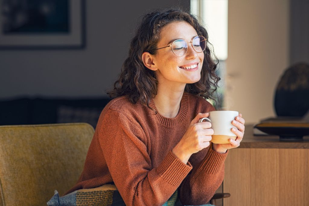 a woman wearing brown long sleeves while holding a white cup