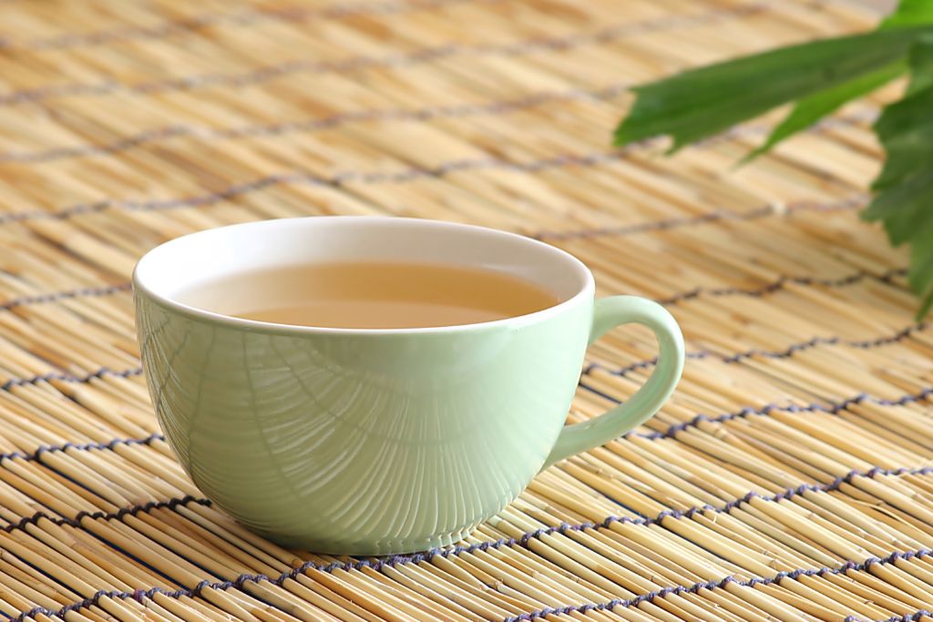 white cup with ginseng tea on a bamboo mat