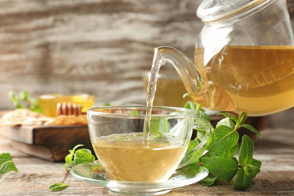 pouring a lemon balm tea in a glass tea cup