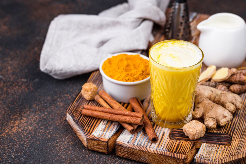 turmeric tea with sliced ginger and powder beside it