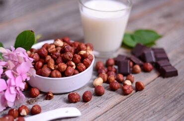 Hazelnut milk and real hazelnut on tip of a wooden table