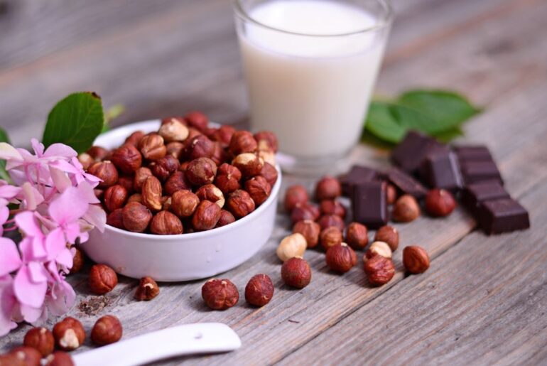 Hazelnut milk and real hazelnut on tip of a wooden table