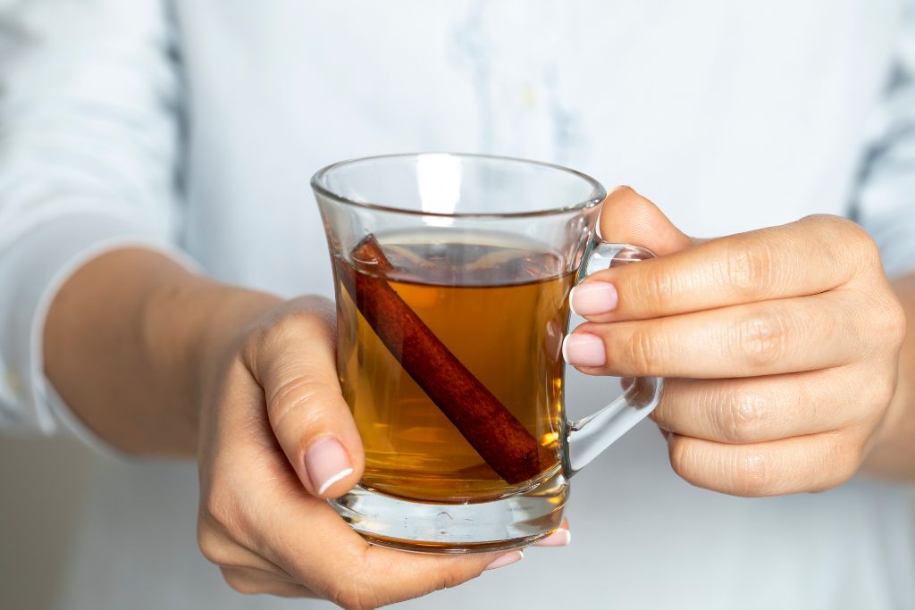 two hands holding a glass of cinnamon tea
