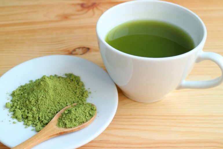 cup of hot matcha tea beside matcha powder