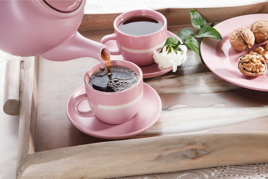 walnut tea being poured from a kettle to a pink cup 